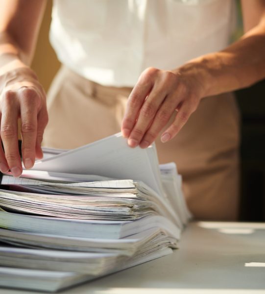 Closeup image of businesswoman searching for document in stack