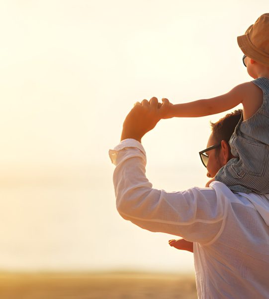 father's day. Dad and baby son playing together outdoors on a summer beach
