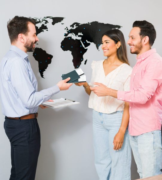 You are all set for your vacations. Sales representative giving passports and plane tickets to a young woman and man for their holiday trip at the travel agency